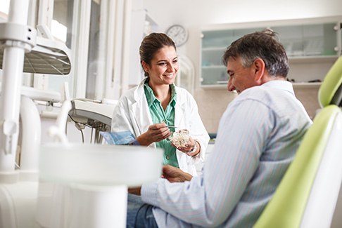 Dentist pointing to model of dental implant