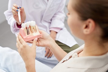 Dentist pointing to model of dental implant