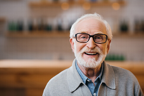 Senior man with glasses in grey jacket smiling