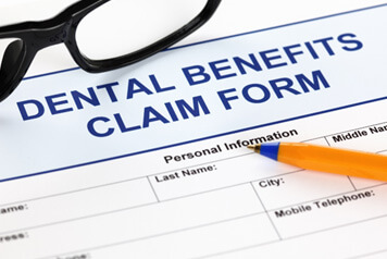 Pen and glasses on top of dental benefits claim form