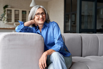 Senior woman leaning against arm of couch
