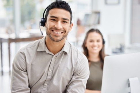 Smiling man wearing headset and sitting at computer