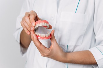 Close-up of dentist holding two dentures in Lenox, MI