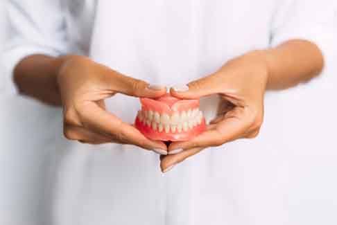 a person holding a pair of new dentures