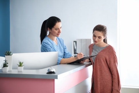 Dental receptionist showing a clipboard to a patient