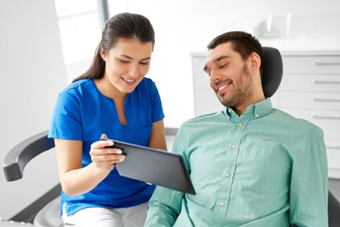 Dental assistant reviewing treatment plan with smiling patient