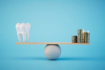 A balance beam holding a model tooth and golden coins 