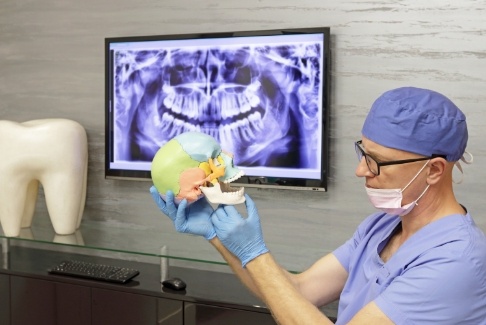 Dentist holding skull and pointing to jaw joints
